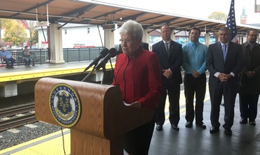 Lieutenant Governor Wyman speaking at podium at Wallingford train station